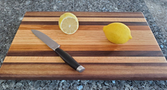 A cutting board, made with 4 species of wood. From the inside out, a wide red oak center, followed by a cherry stripe, a walnut stipe, a maple stripe, and a slightly wider walnut strip (which also shows a lighter sapwood)